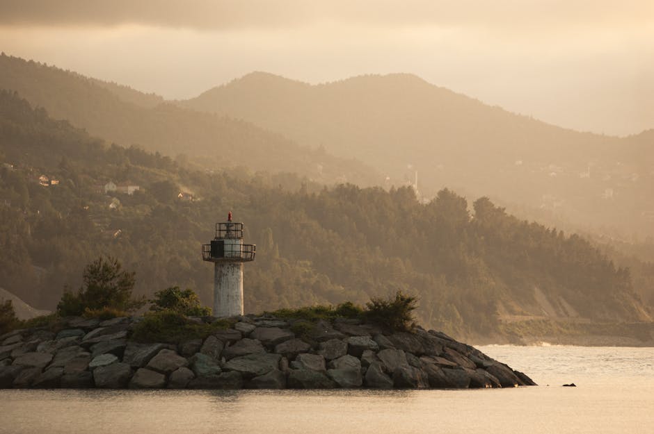 Dramatic view of Abana lighthouse in Türkiye, surrounded by serene sea and hazy mountains.