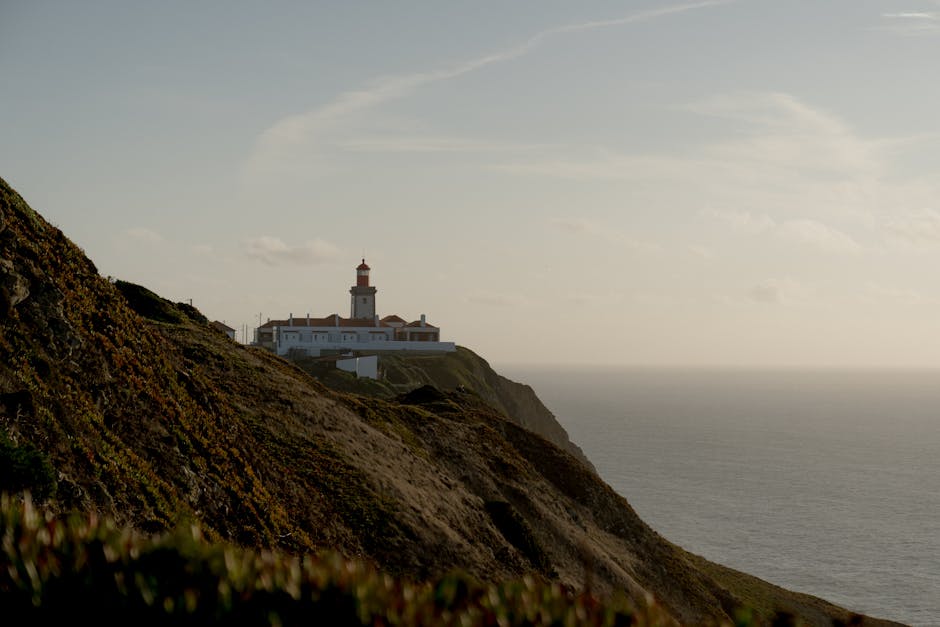 Tranquil sunset view of a lighthouse perched on a rugged coastal cliff overlooking the vast ocean.