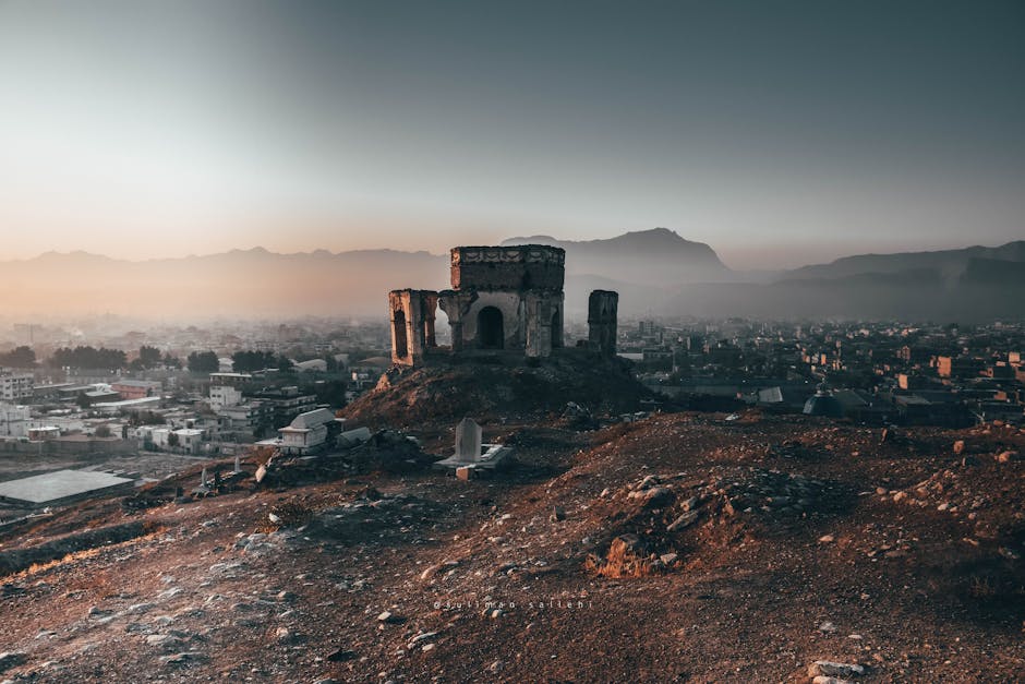 Scenic view of ancient ruins and cityscape with mountains at sunset.